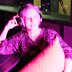 Pink hue podcast guest - phot of white middle aged woman in headphones holding cushion