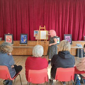 One of our tutors demonstrating how to paint a circus-themed poster in gouache
