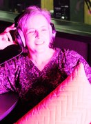 Pink hue podcast guest - phot of white middle aged woman in headphones holding cushion