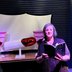 Vagina Museum edited anthology reading white older woman on stage reading - with glittery tampon and mooncup behind